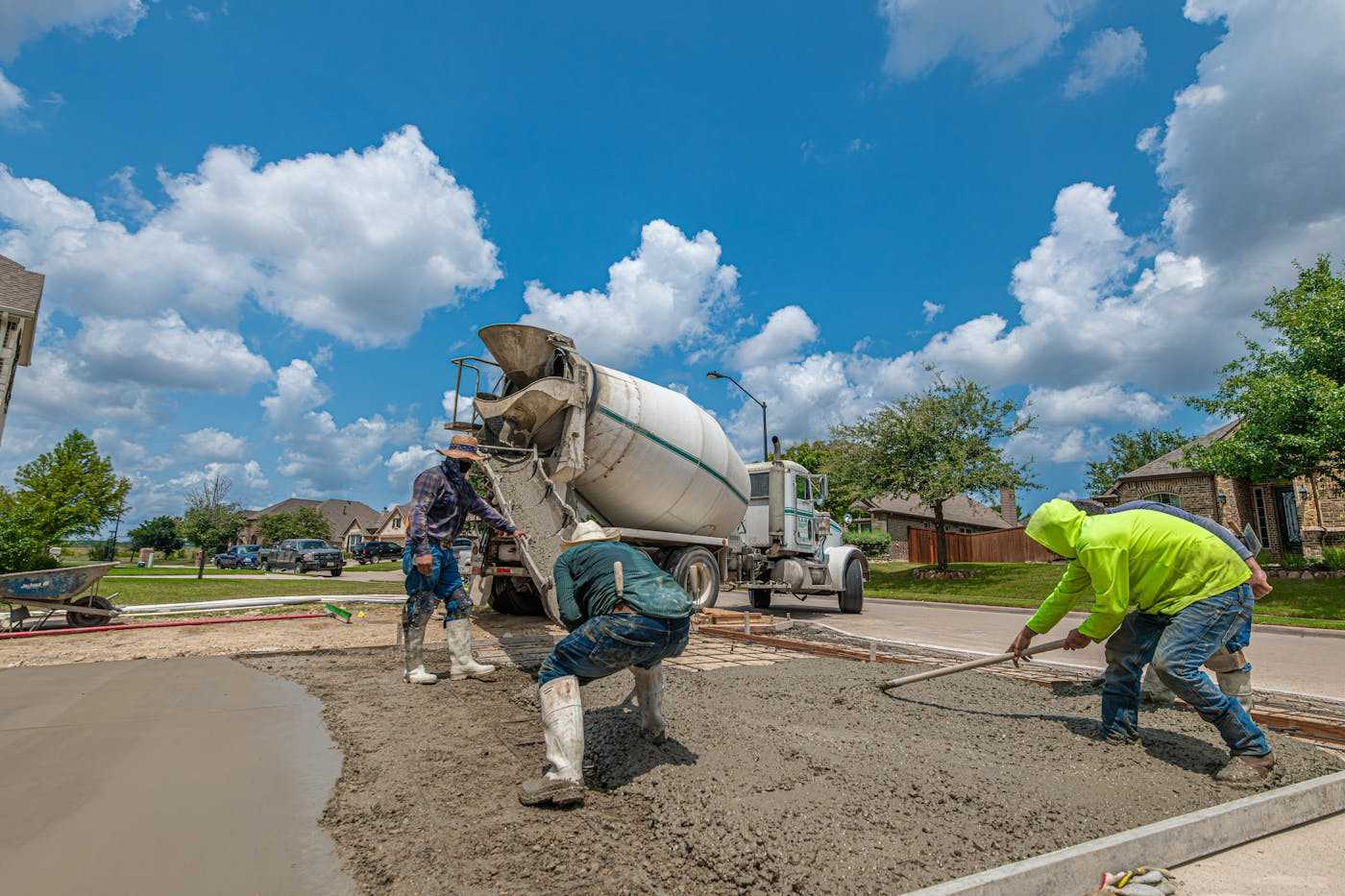 Workers pouring and finishing a concrete driveway
